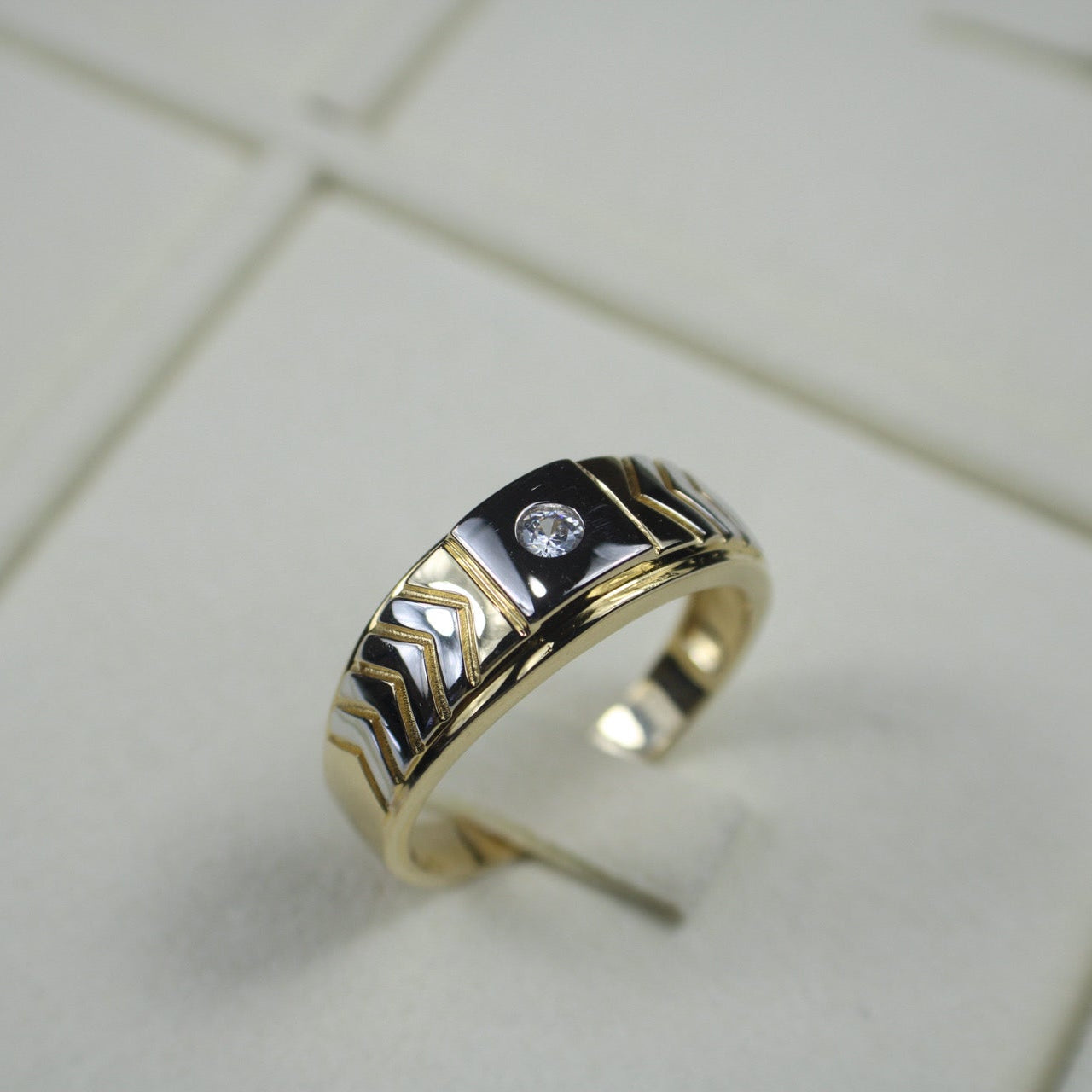 Gold ring with a diamond on a tiled surface