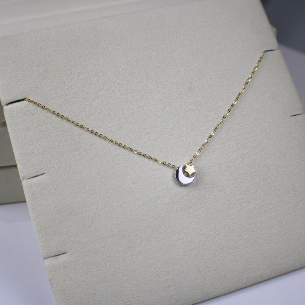 Gold necklace with a heart pendant on a light gray stand