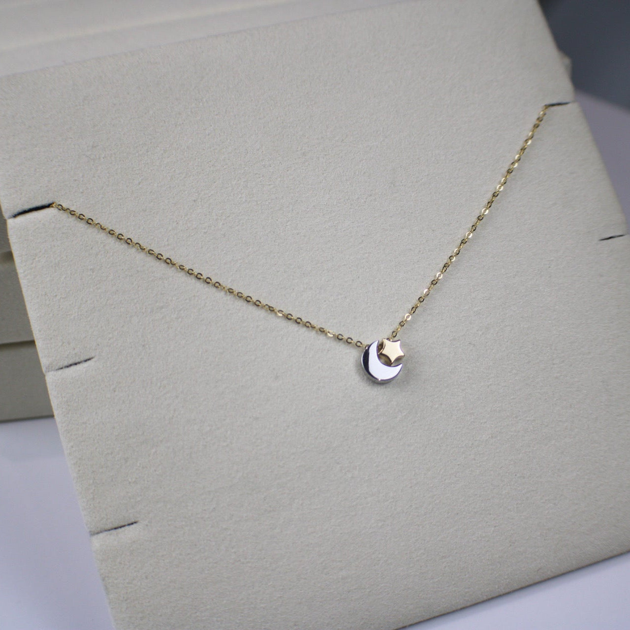 Gold necklace with a heart pendant on a light gray stand