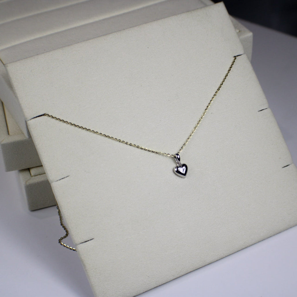 Necklace with a heart pendant on a white stand