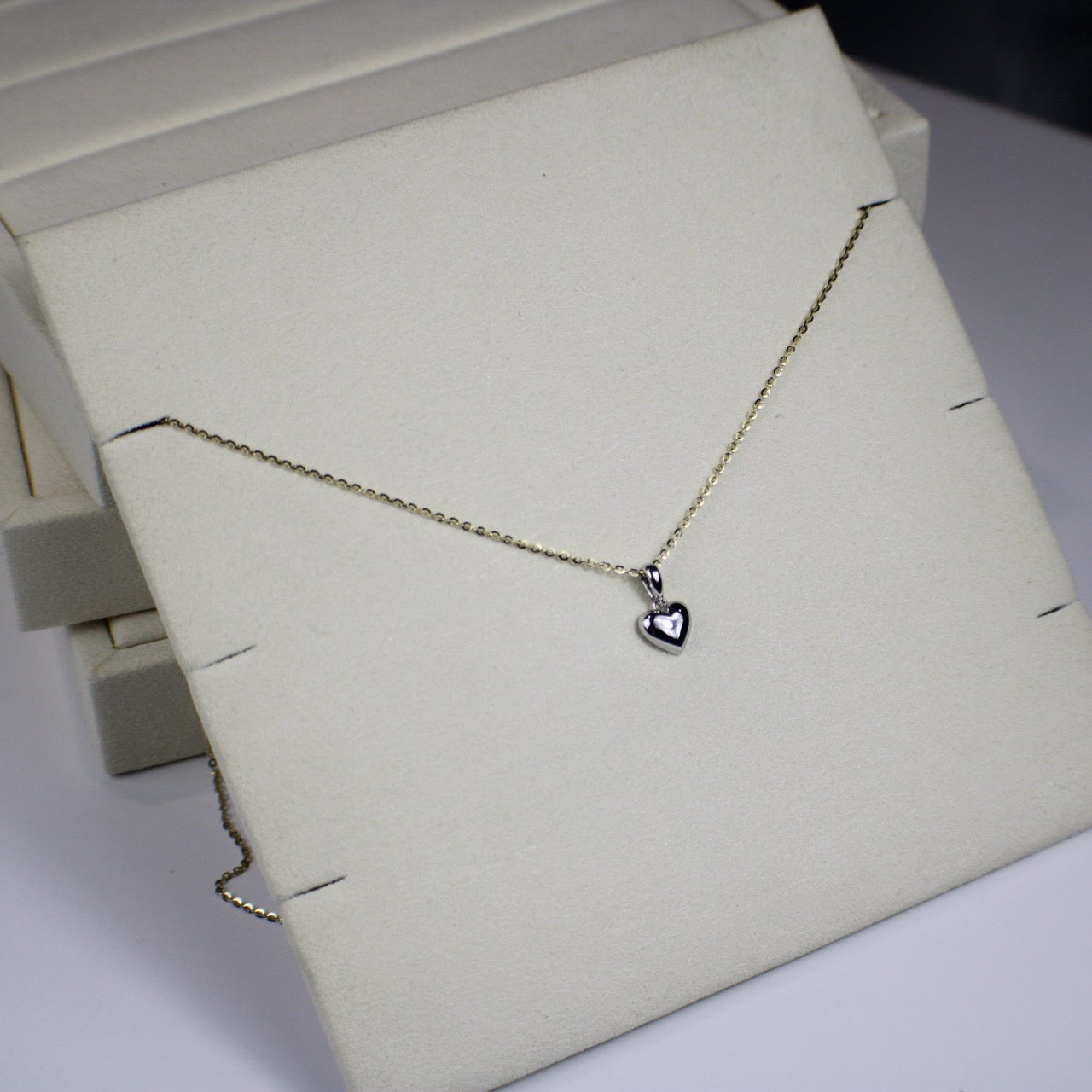 Necklace with a heart pendant on a white stand