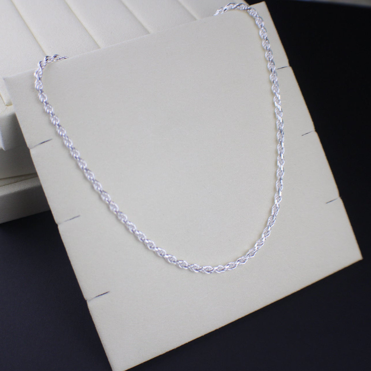 Silver chain necklace on a white box with a dark background