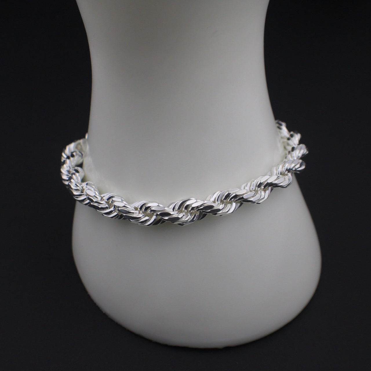 Silver braided anklet on a white mannequin foot against a black background