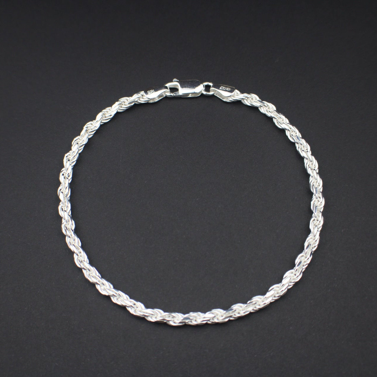 Silver braided bracelet on a dark gray background