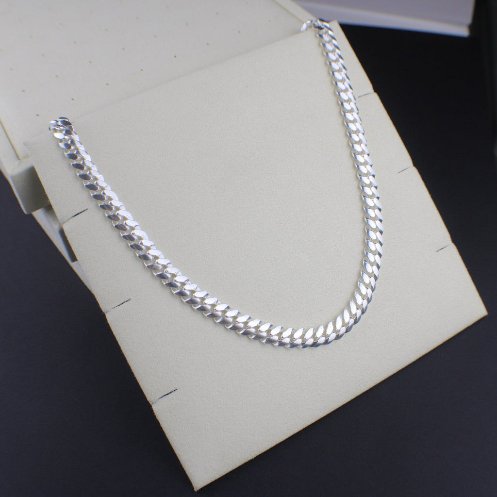 Silver chain necklace on a white box with a dark background
